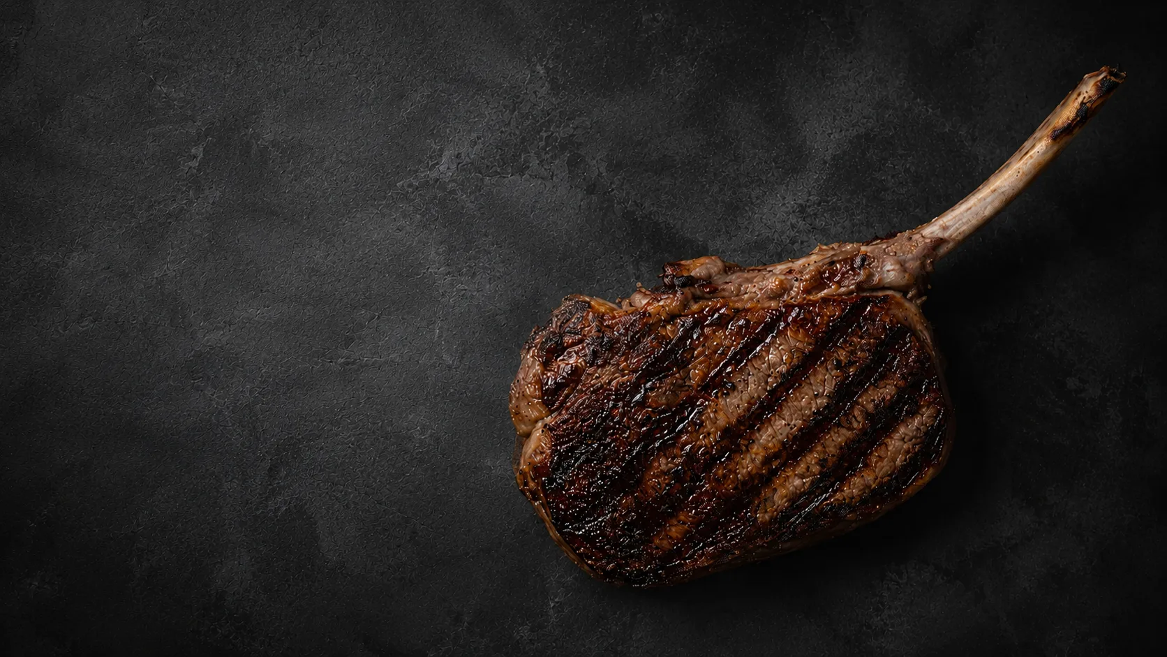 Gegrilltes Tomahawk-Steak mit Grillmuster auf dunklem Schiefer