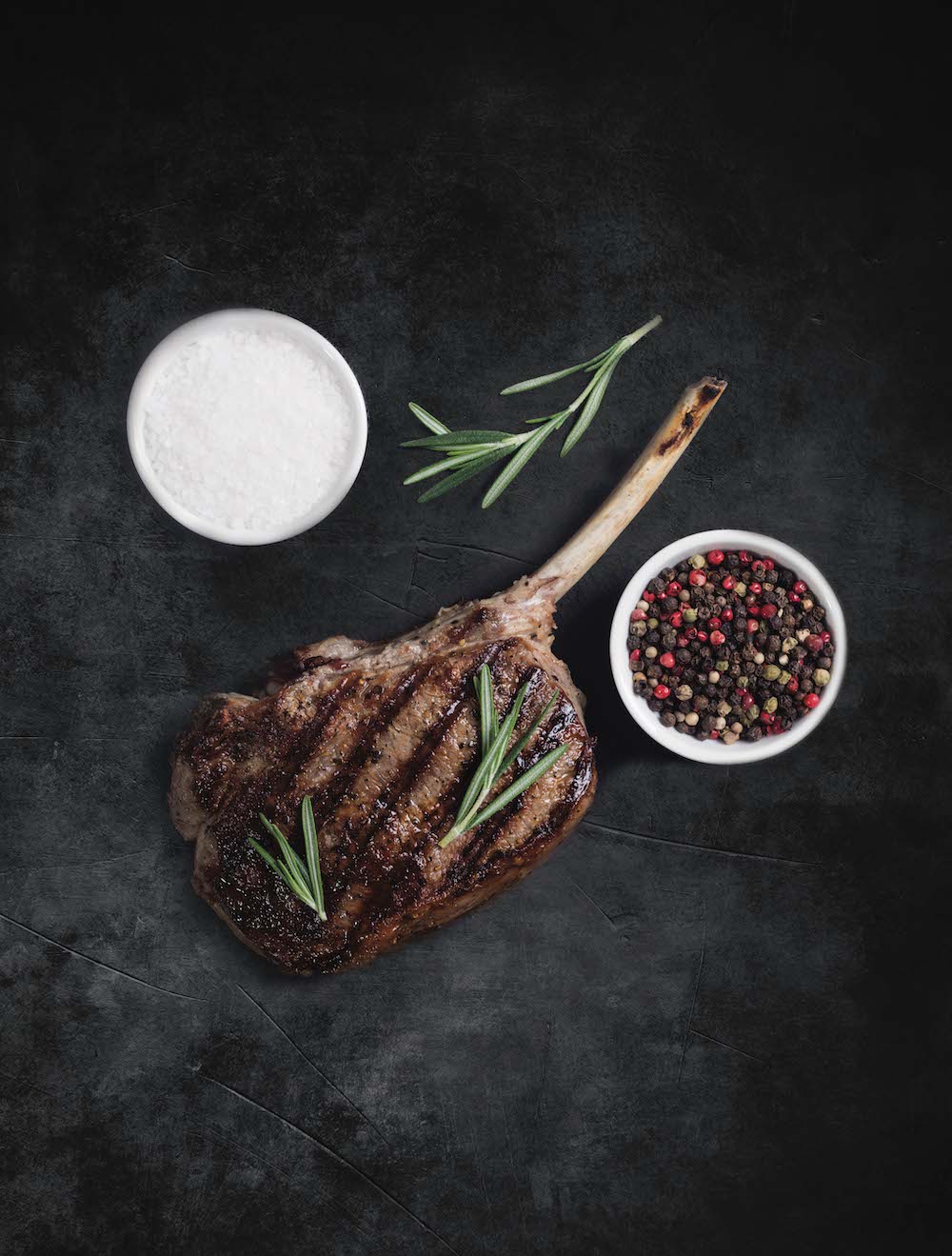 Gegrilltes Tomahawk-Steak mit Knochen auf dunklem Schiefer